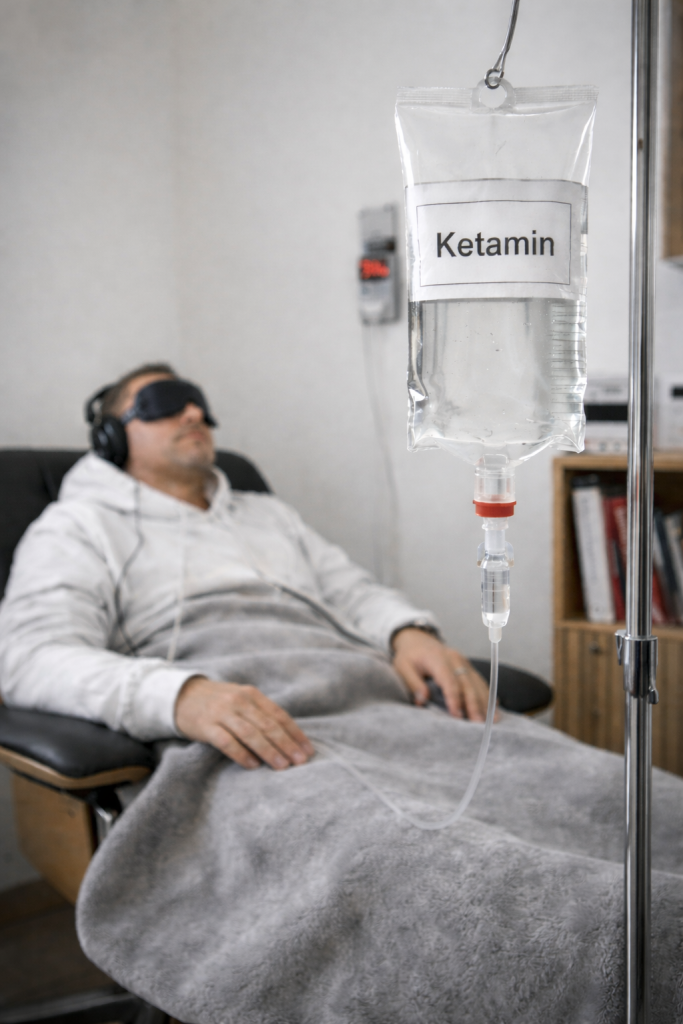 Ketamin-Therapie mit Infusion: medizinische Ketamin-Behandlung einer liegenden Person mit Schlafmaske und Kopfhörern.