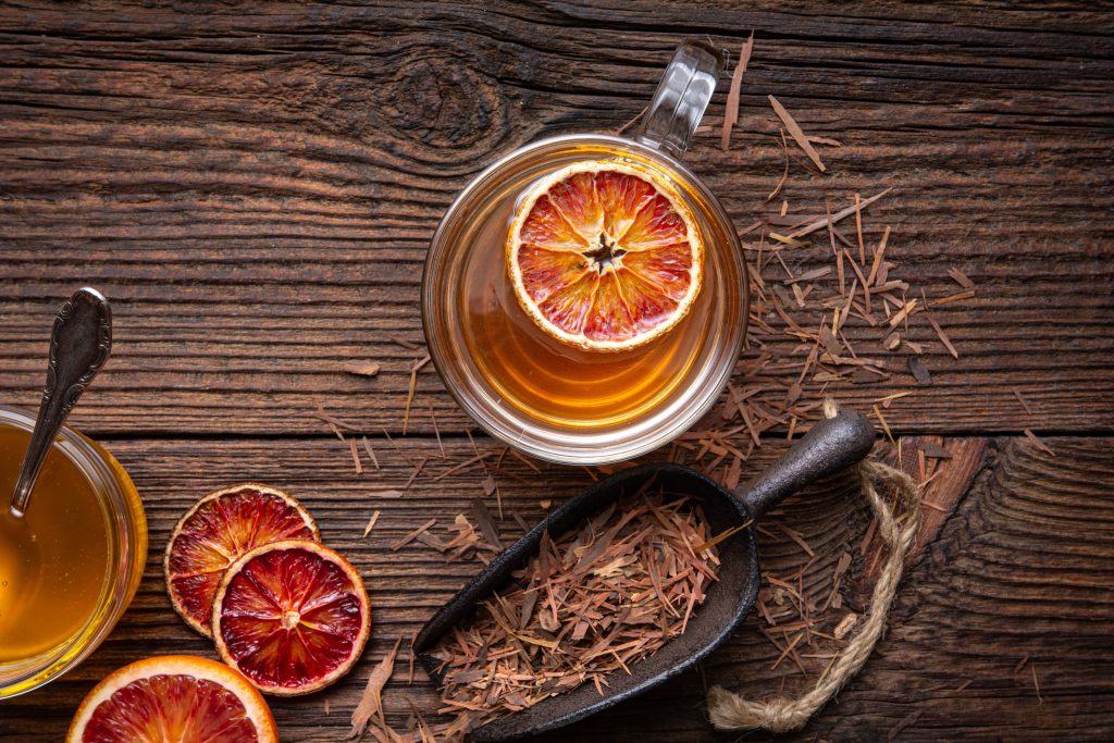 Lapacho-Tee aus der Rinde von Tabebuia avellanedae mit getrockneter Lapacho-Rinde, Blutorange und Honig als Serviervorschlag.